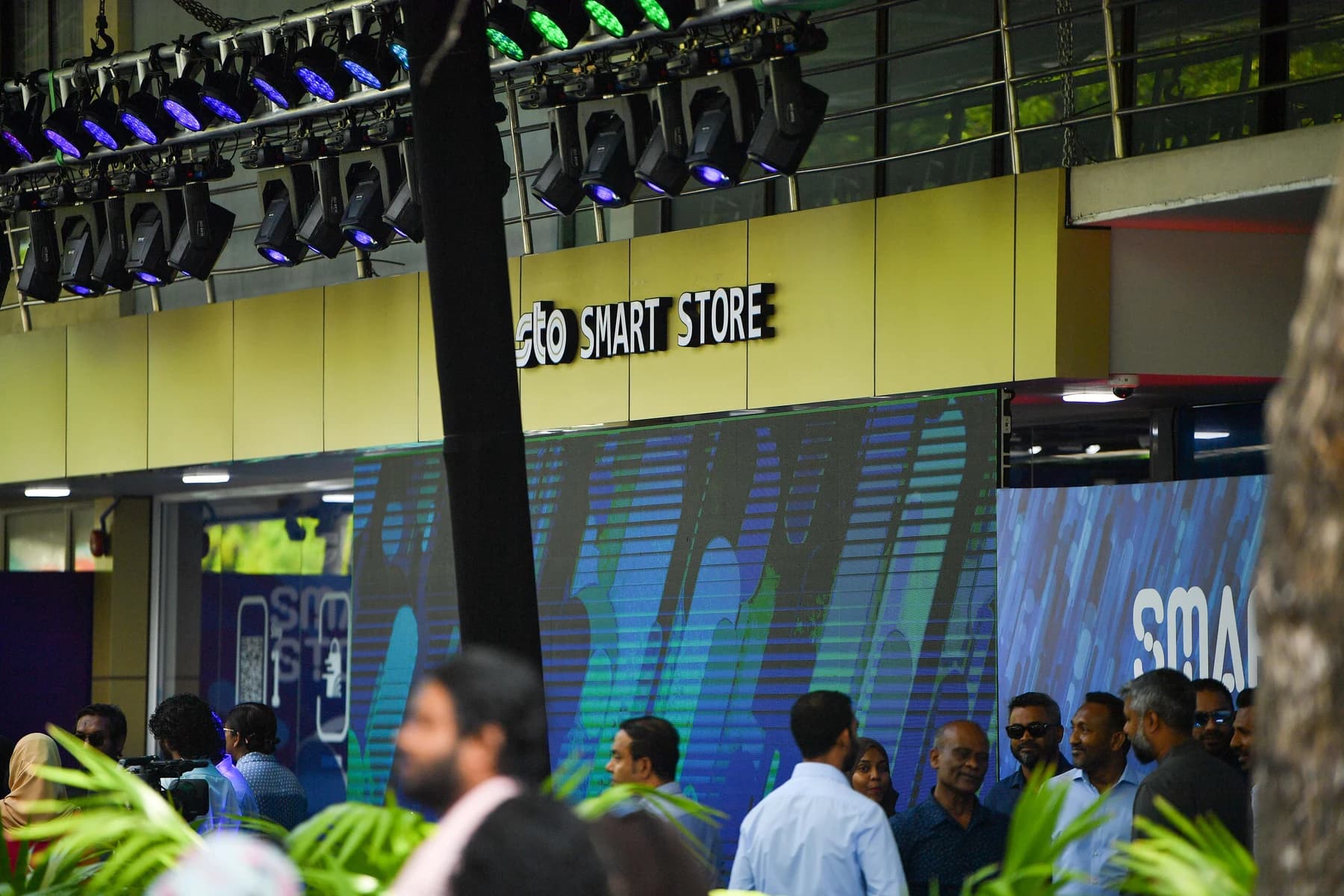 The front of a shop with an 'sto Smart Store' sign above a decorated entrance, with people gathered outside.