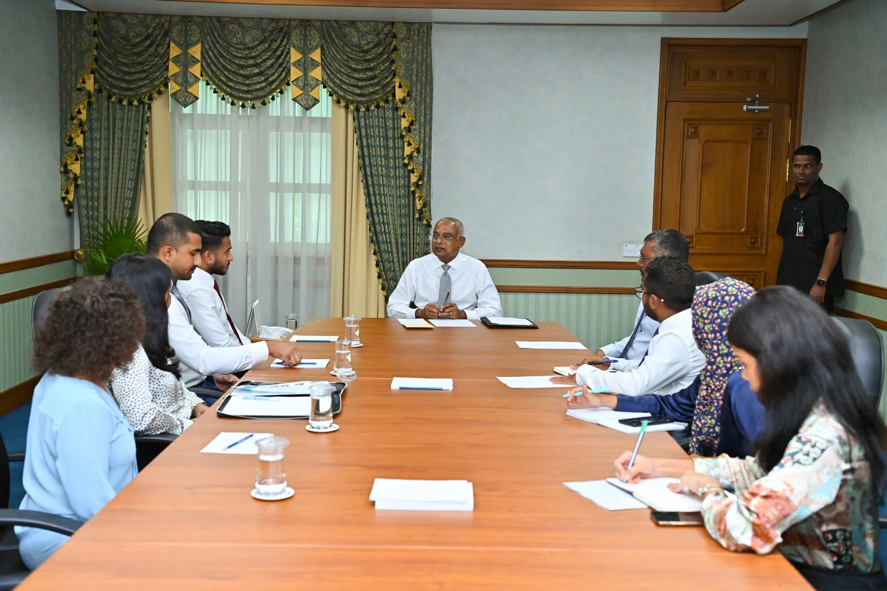 Former President Ibrahim Mohamed Solih at the head of a long meeting table, with members of a migrant workers’ rights group seated along both sides.