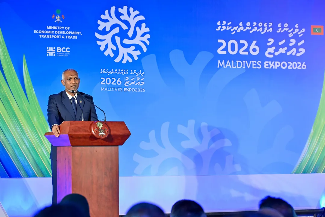 President Mohamed Muizzu speaks at a wooden lectern in front of a blue Maldives Expo 2026 backdrop.