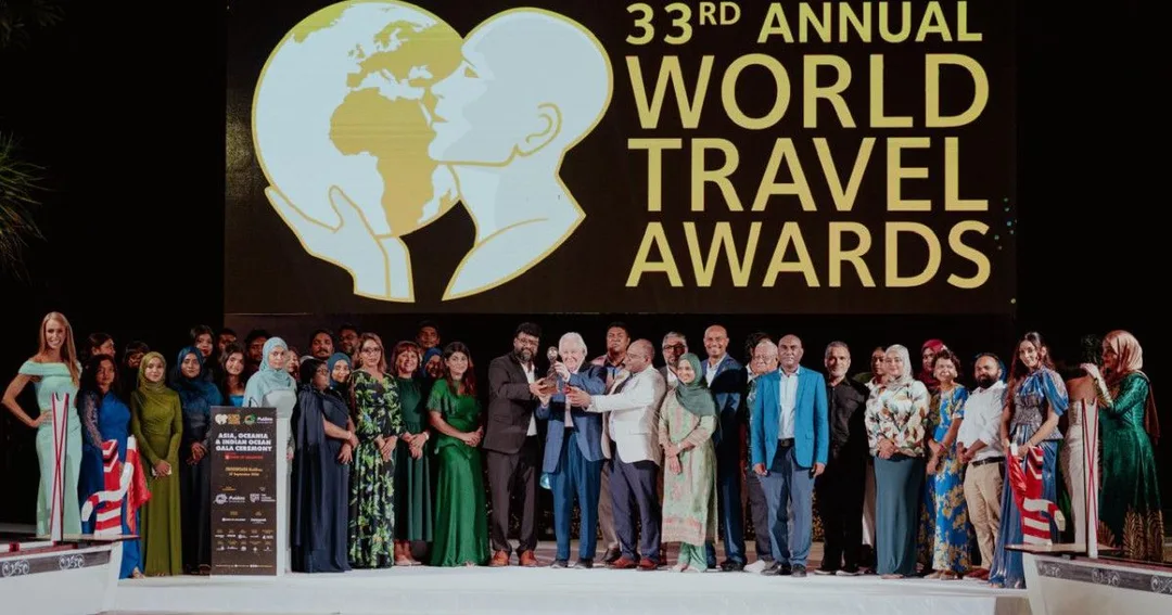 Award winners and officials pose on a stage beneath a large screen reading 33rd Annual World Travel Awards.